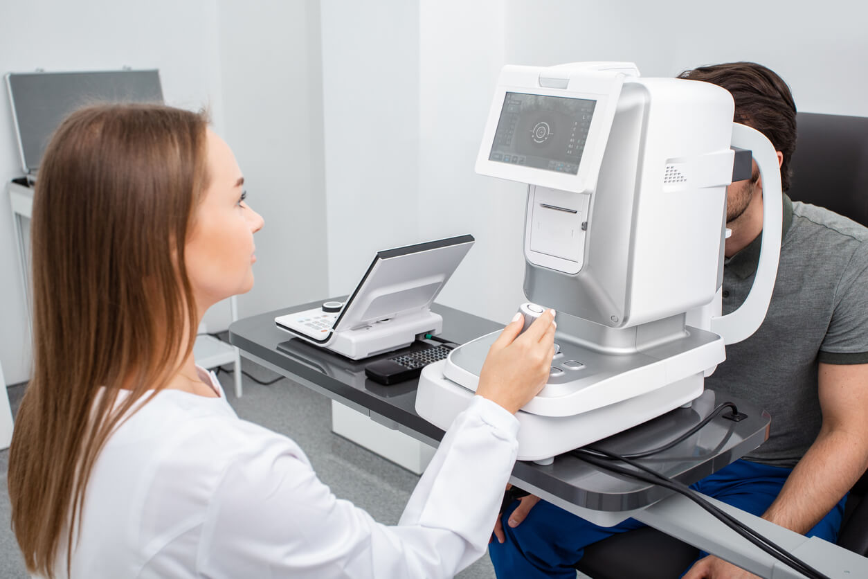 A female optometrist looking at a screen of ophthalmic autorefractor.