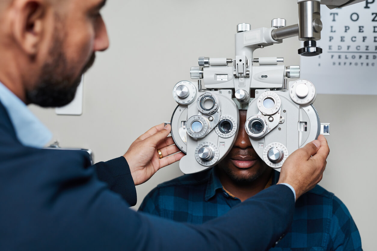 An optometrist adjusts a phoropter on his patient’s eyes.